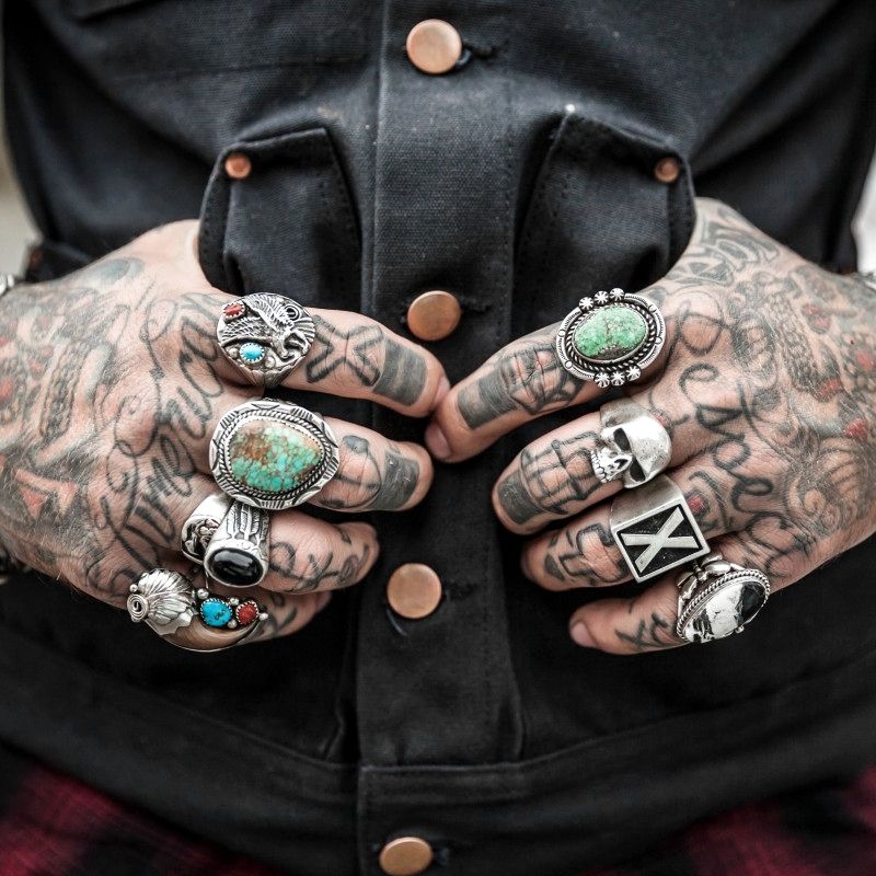 Heavily tattooed hands wearing silver and turquoise rings