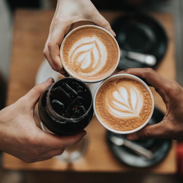 Friends toasting with latte art coffees